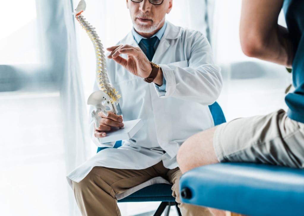 Physiotherapist explaining the nerves in the spine before treating tingling sensation in back.