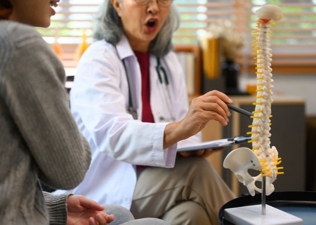 Chiropractor explaining to patient with skeletal model how to heal from a herniated disc. 