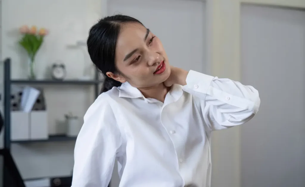 An office worker massaging the tense area of her shoulder.