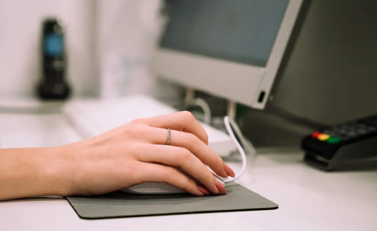 An office worker using a computer mouse, which is often attributed to mouse shoulder.