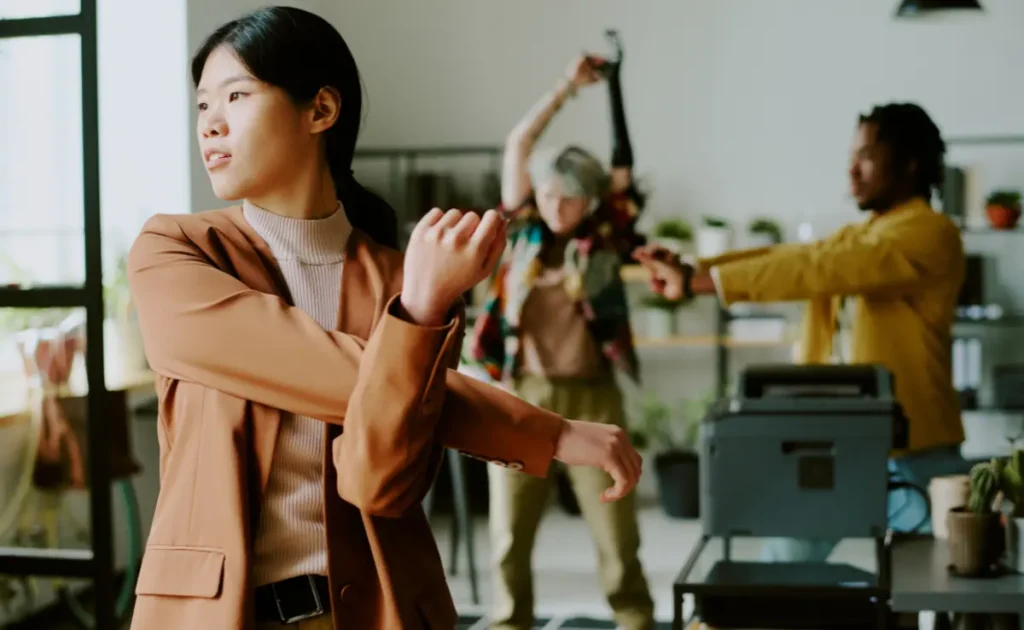 A team of office workers doing stretches to avoid mouse shoulder pain.
